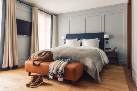 Doppelbett mit kleinem Nachttischchen im Taube Deluxe Zimmer