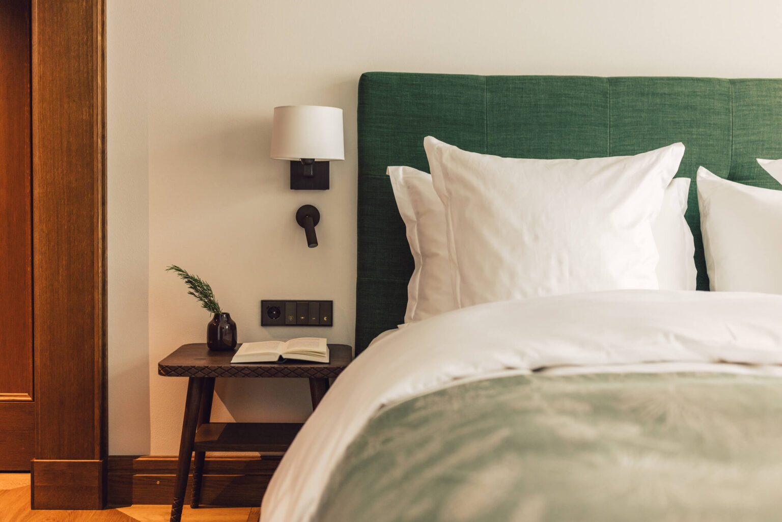 Doppelbett mit kleinem Nachttischchen im Taube Deluxe Zimmer