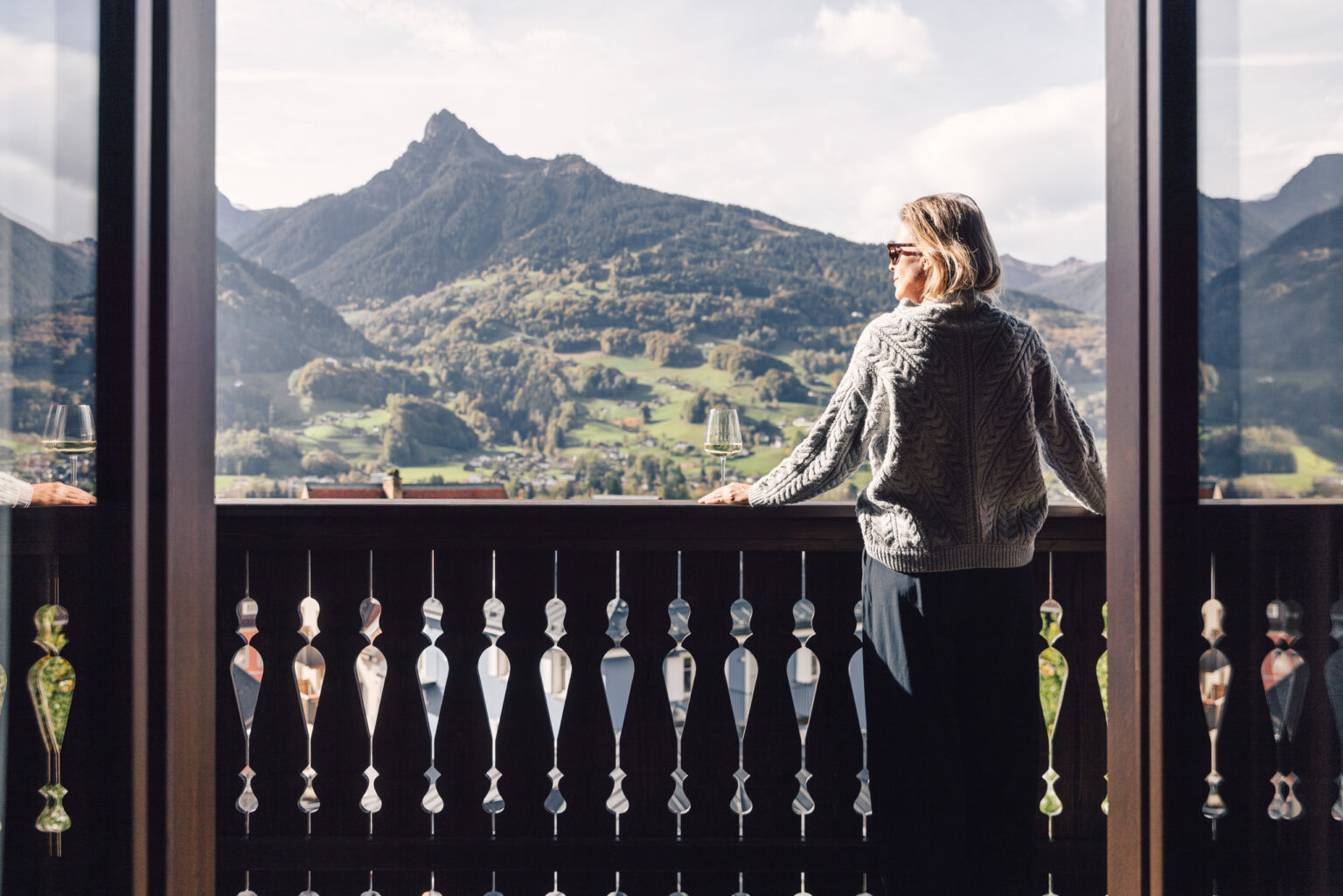 Frau genießt den Blick auf das Schrunser Bergpanorama vom Balkon der Adler Suite im Posthotel Taube aus.