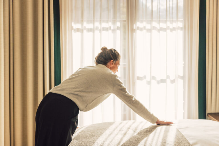 Angestellte im Bereich Housekeeping bereitet das Bett im Hotelzimmer für die Gäste vor.