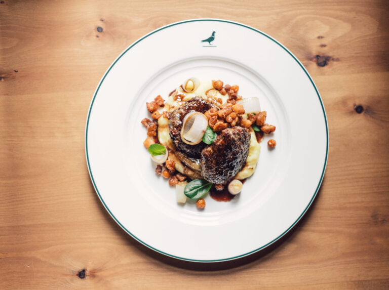 Ein köstlicher Braten, liebevoll auf einem Teller des Posthotel Taube serviert.