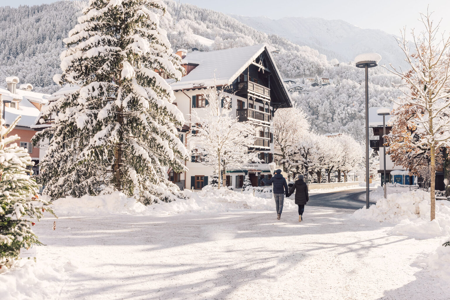 Außenansicht im Winter, Paar spaziert im Schnee – Posthotel Taube in Schruns
